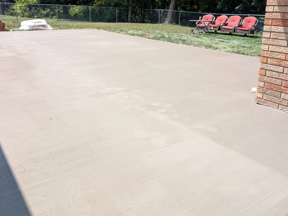 Freshly poured broom-finish concrete patio behind a brick ranch home in Dearborn Heights, MI